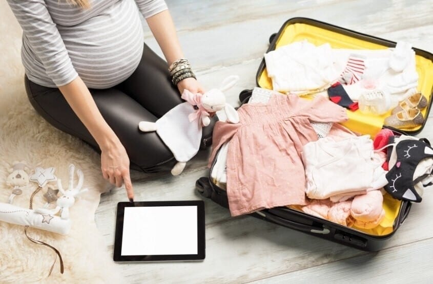 A pregnant woman packing her bags before travel.