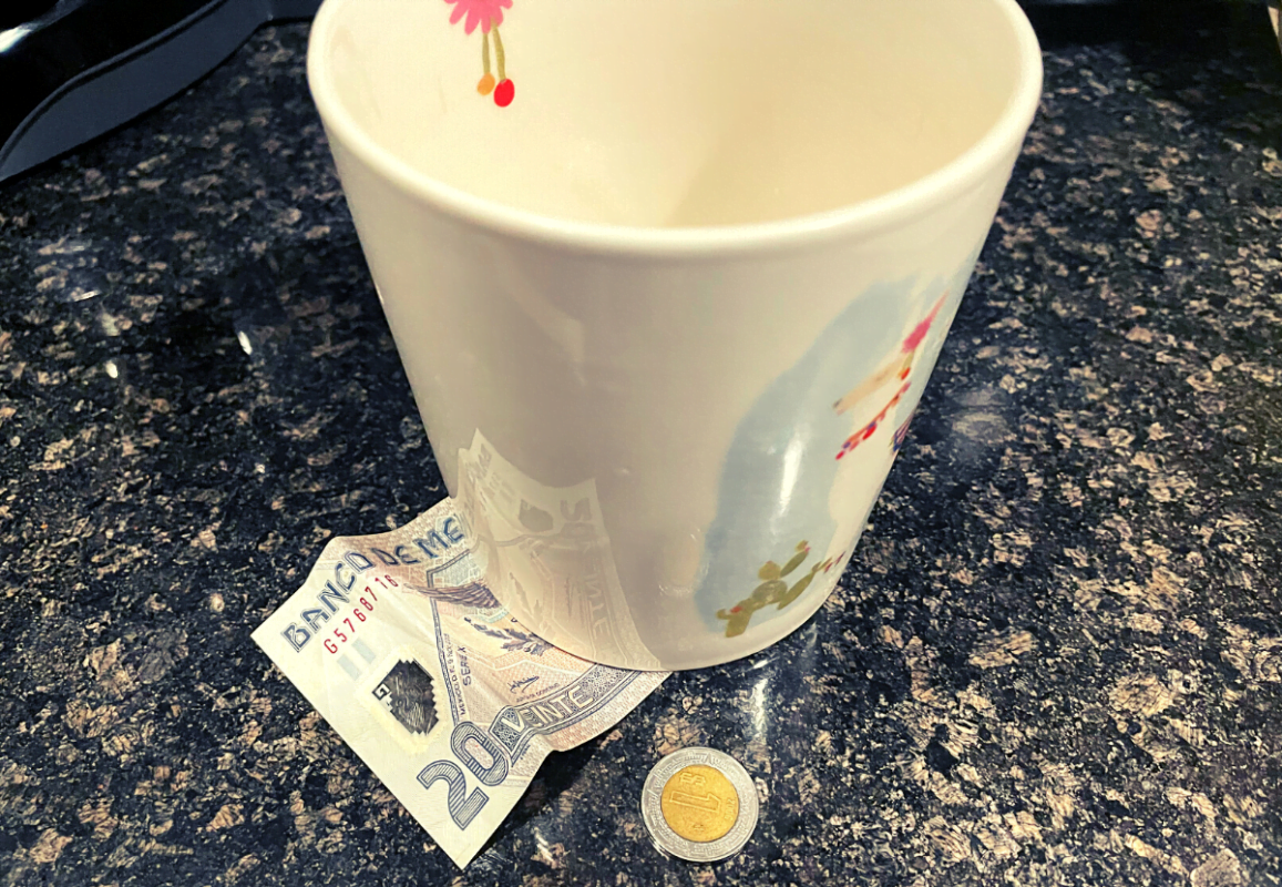 Twenty peso tip left under a cup.