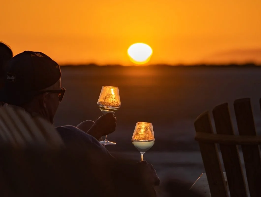 A couple watching an amazing desert sunset in Baja California with a glass of wine