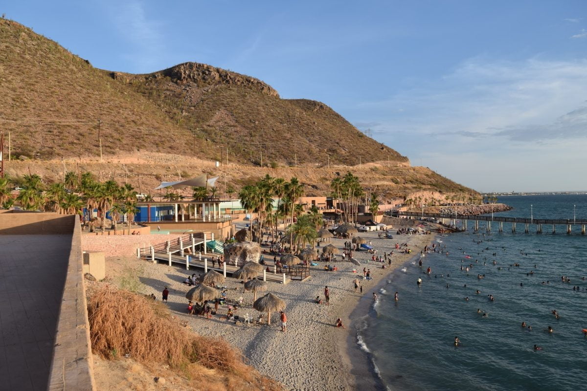 a shot of playa el coromuel with people and buildings in la paz, mexico