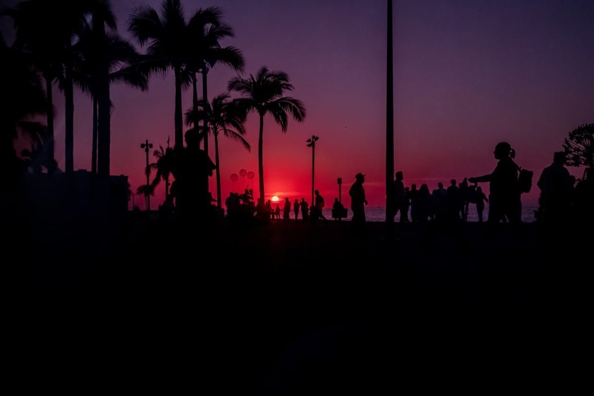 a group of people standing in front of a sunset in Malecon, San Felipe