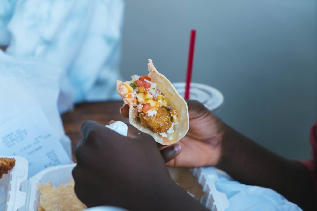 person holding a fish taco in ensenada